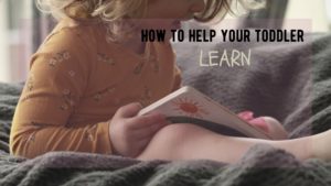 toddler sits in yellow shirt on cozy cushion reading a book