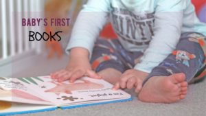 Baby sits on the ground reading baby books about animals