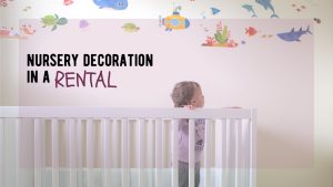 baby stands in a crib looking at the wall decor in her nursery